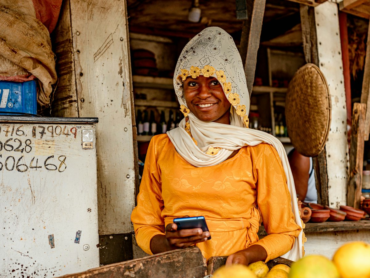A shopkeeper smiling as she checks her phone at her stall