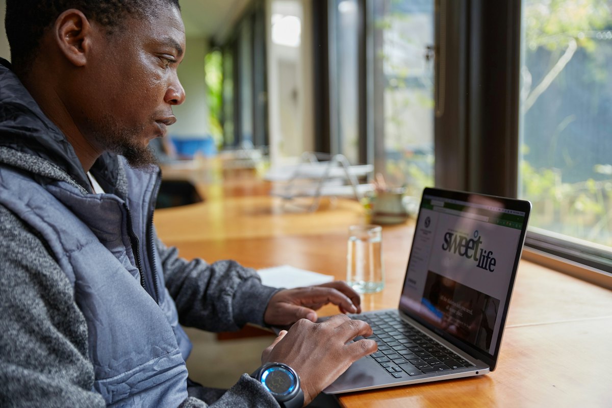A man checking figures on his laptop at a desk by the window