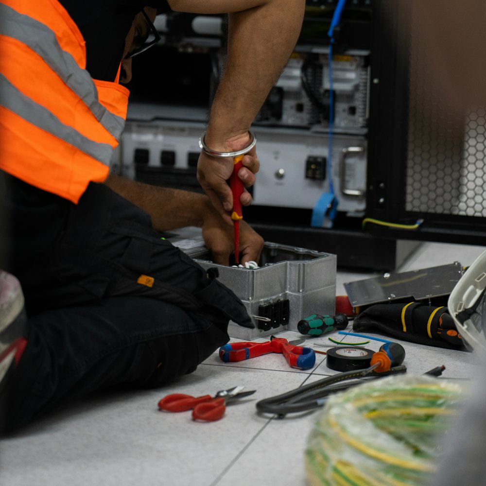 A technician in a high-visibility vest working on a network rack